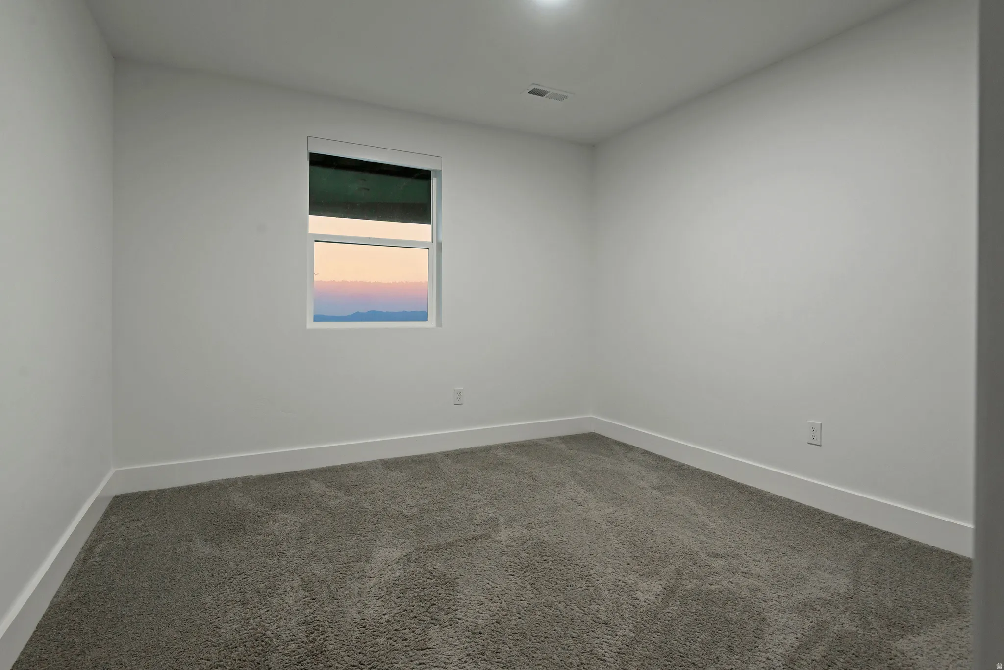 Neutral white walls featuring a single window, recessed lighting, and gray carpet flooring