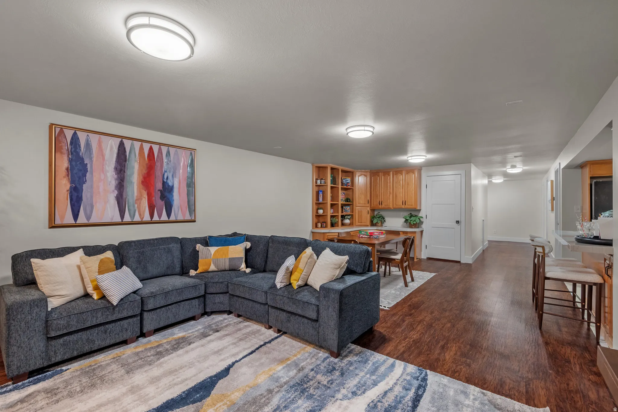 Spacious living area featuring wood-finish flooring, recessed lighting, built-in shelving, and light wood cabinetry