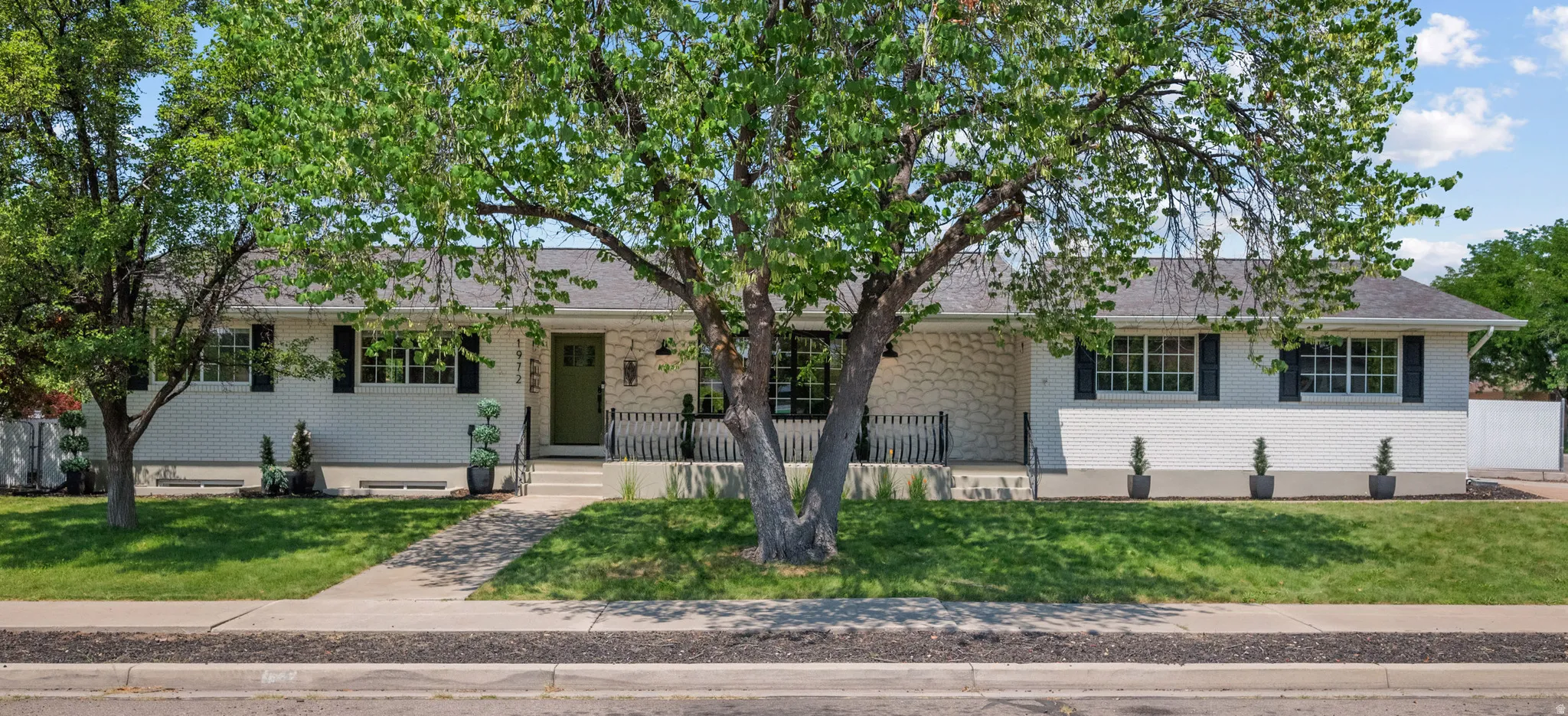 Ranch-style exterior featuring white brick and stone accents