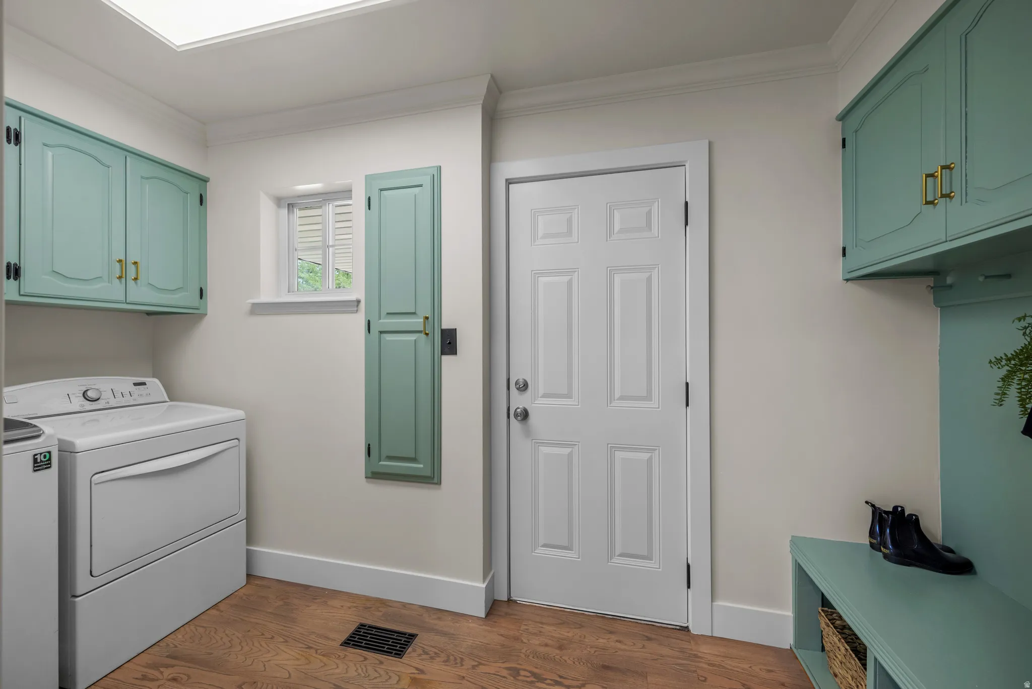 Laundry area featuring wood-finish flooring, light-colored walls, and a white paneled door