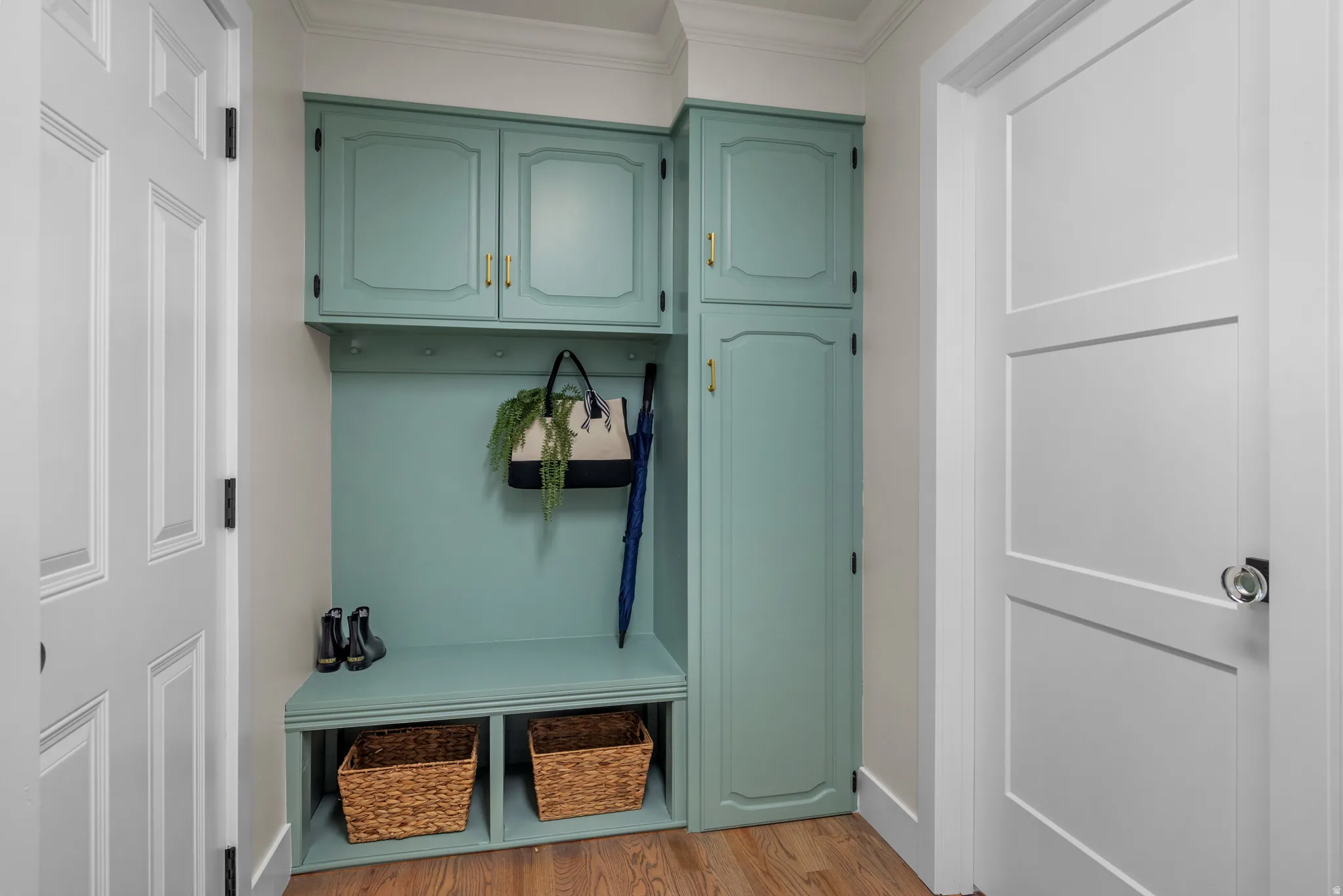 Built-in drop zone featuring custom cabinetry, integrated bench seating, and wall-mounted storage hooks