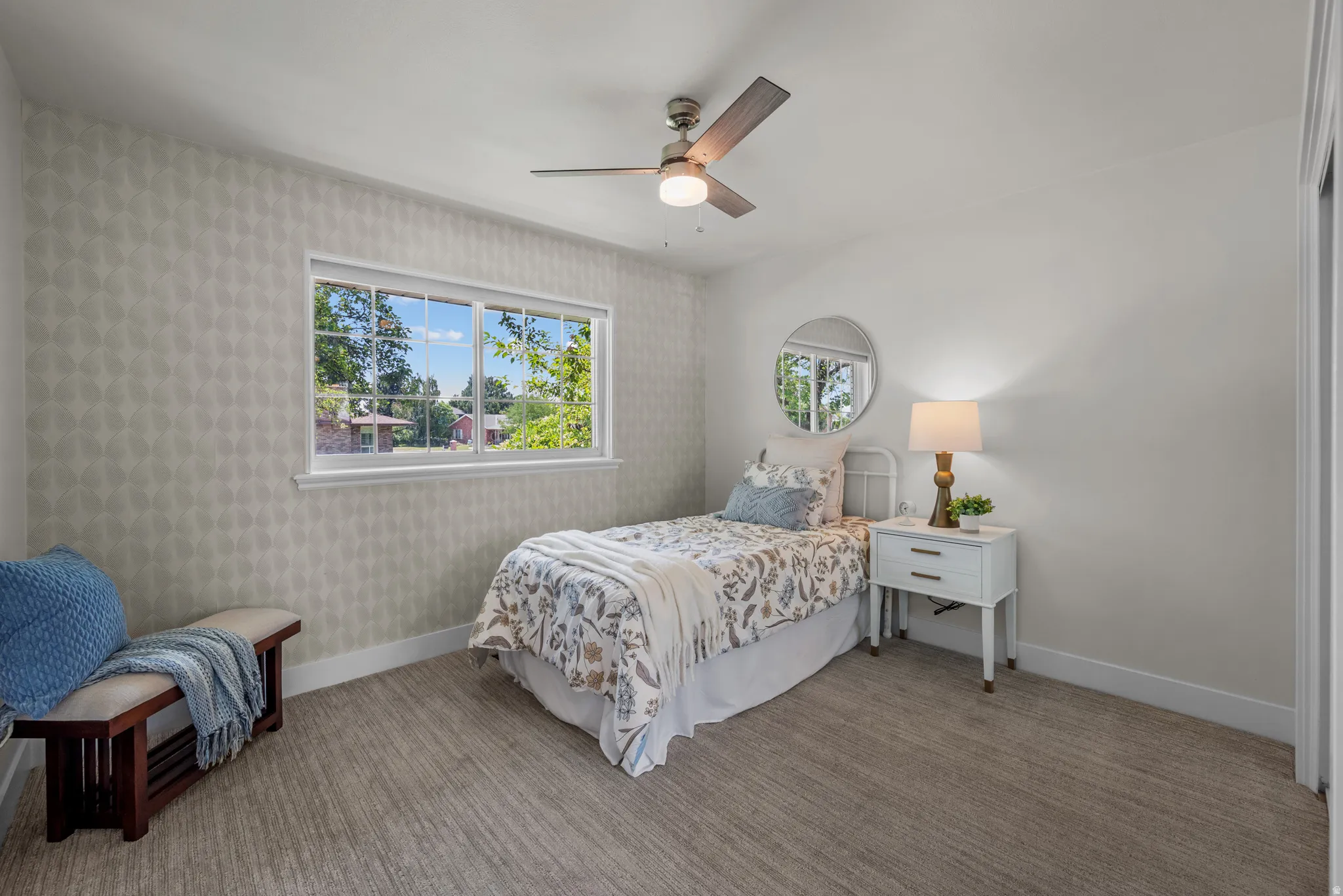 Room featuring patterned accent wall, white trim, and light-toned carpet flooring