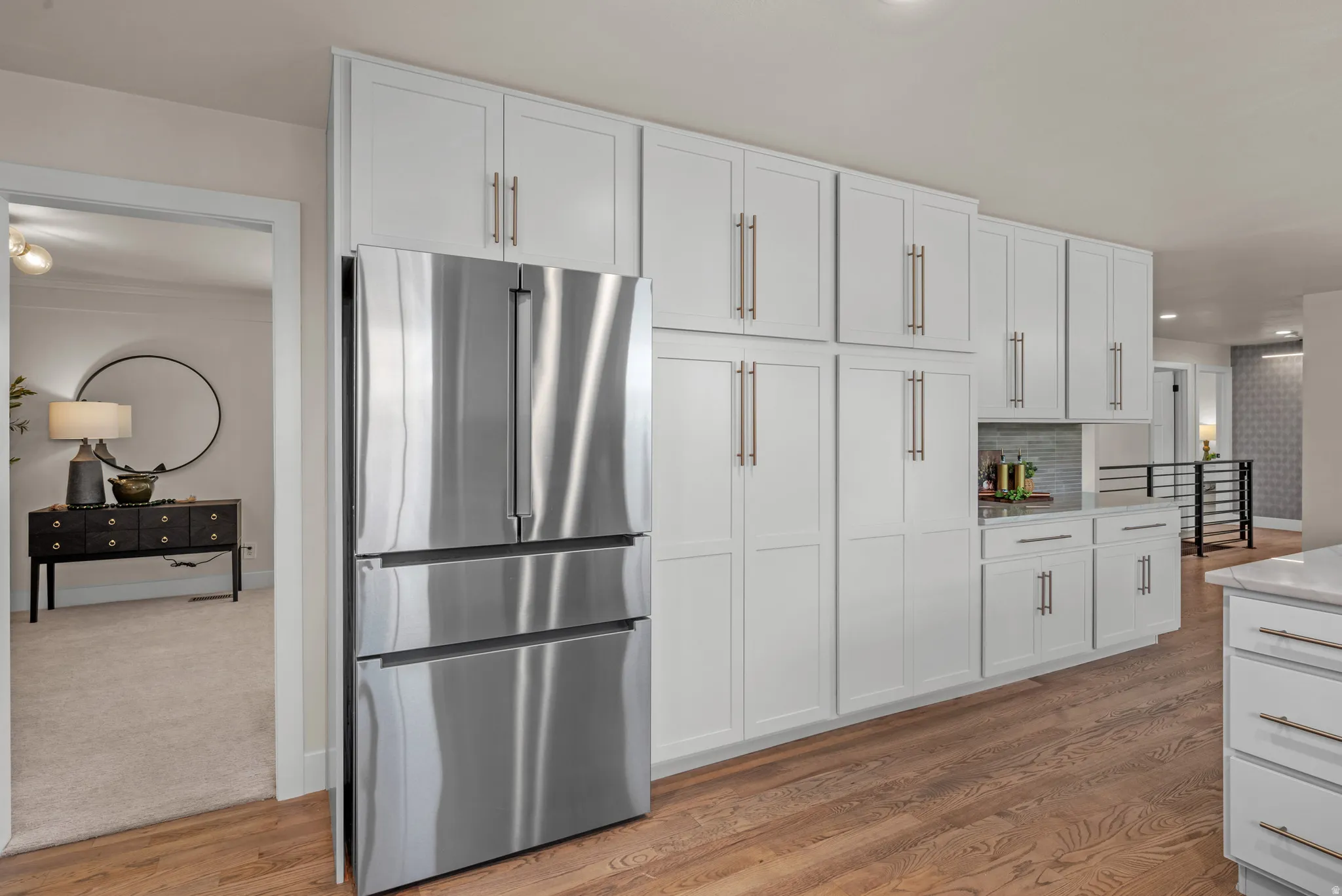 Kitchen featuring extensive white cabinetry, stainless steel refrigerator, light wood-finish flooring, and a tiled backsplash