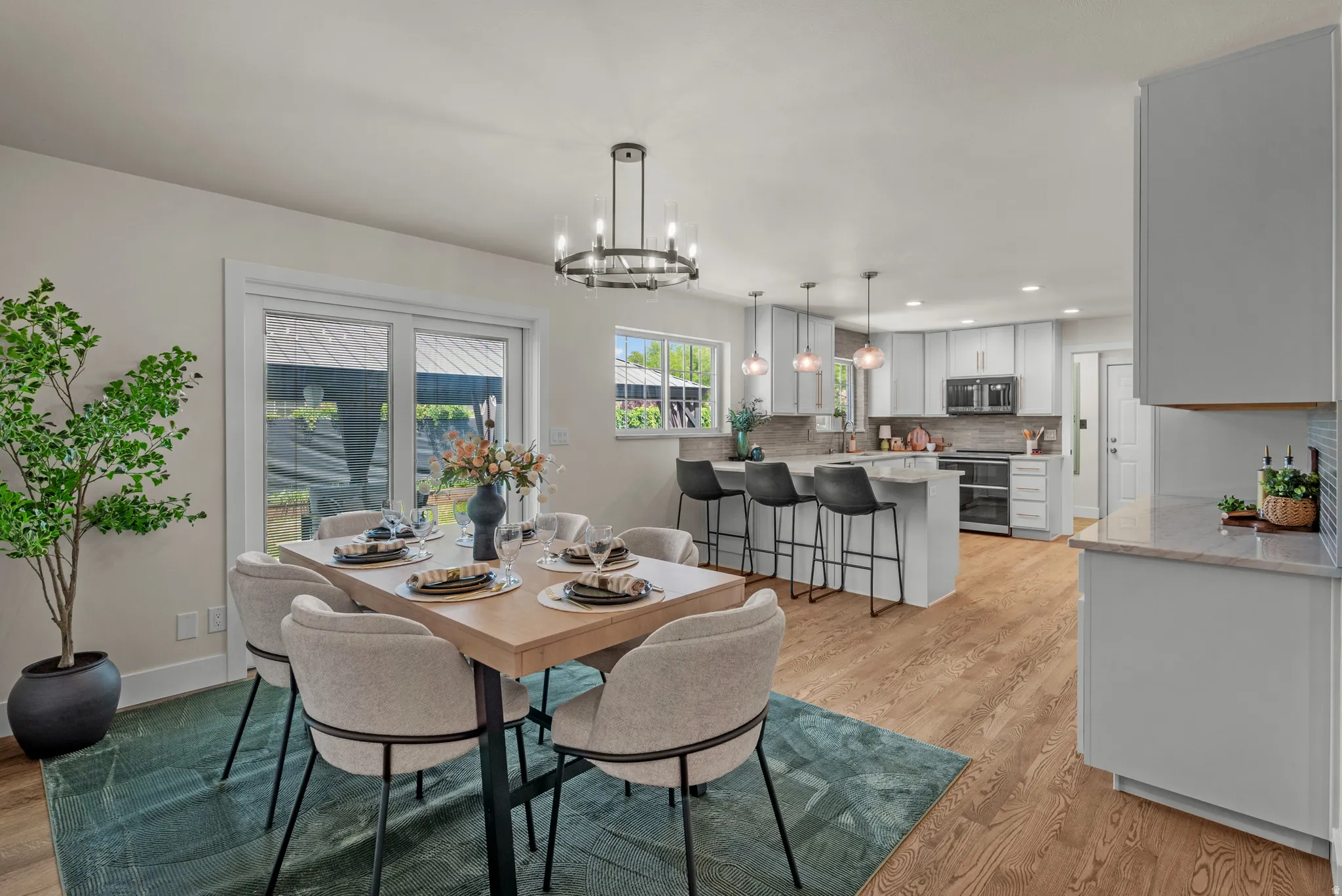 Open concept living space featuring wood-finish flooring, a contemporary dining area with a circular chandelier, and sliding glass doors