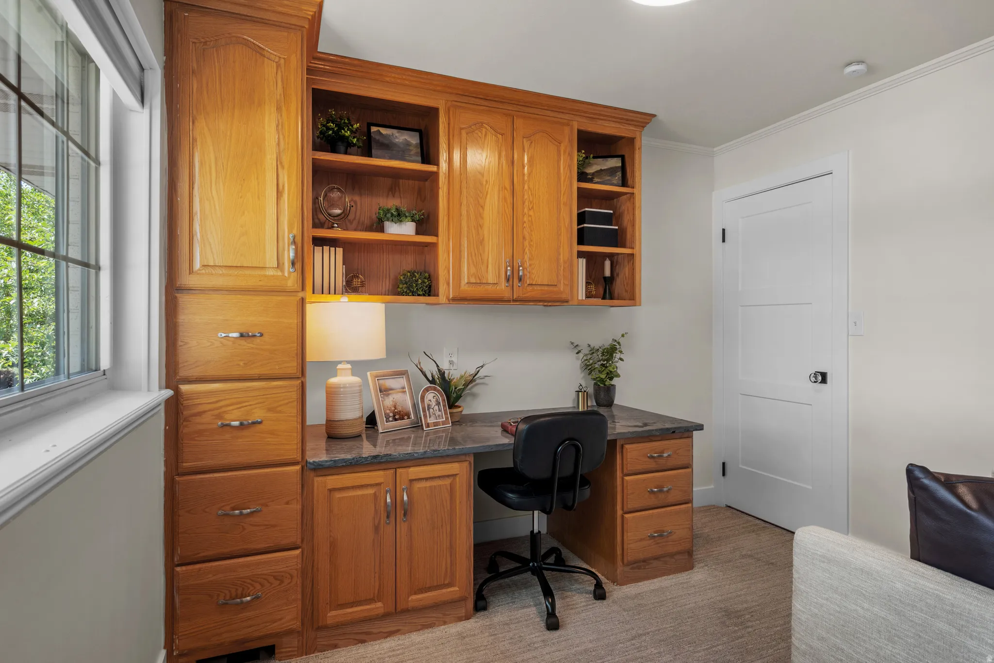 Built-in wood cabinetry with a dark speckled countertop, integrated desk, and open shelving