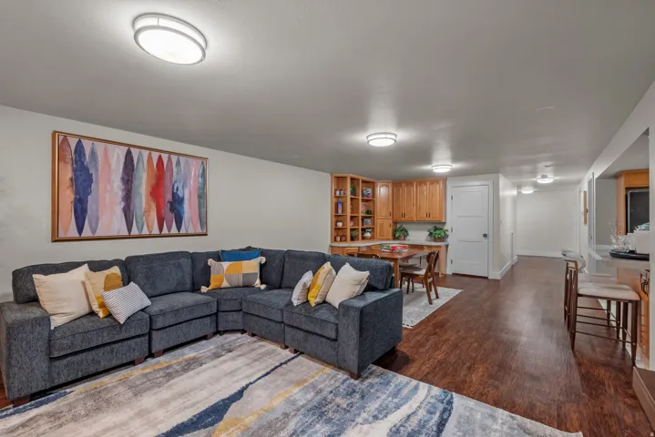 Spacious living area featuring wood-finish flooring, recessed lighting, built-in shelving, and light wood cabinetry