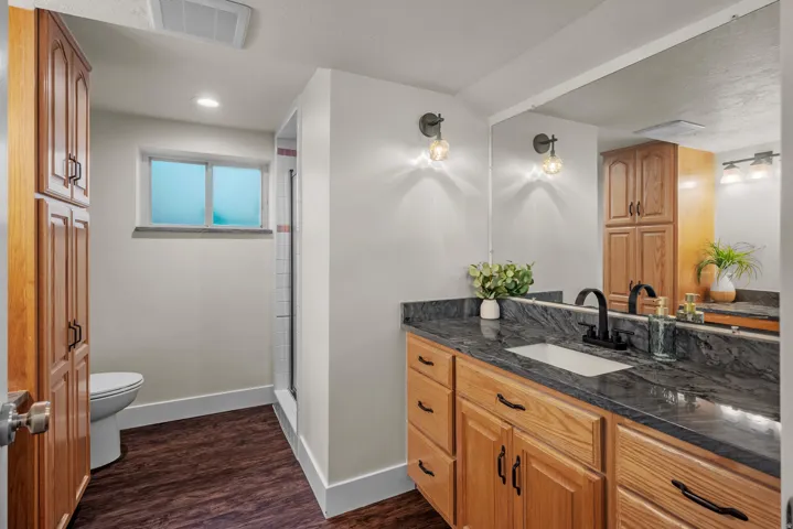 Bathroom featuring a single vanity with stone countertop, integrated sink, and matte black faucet