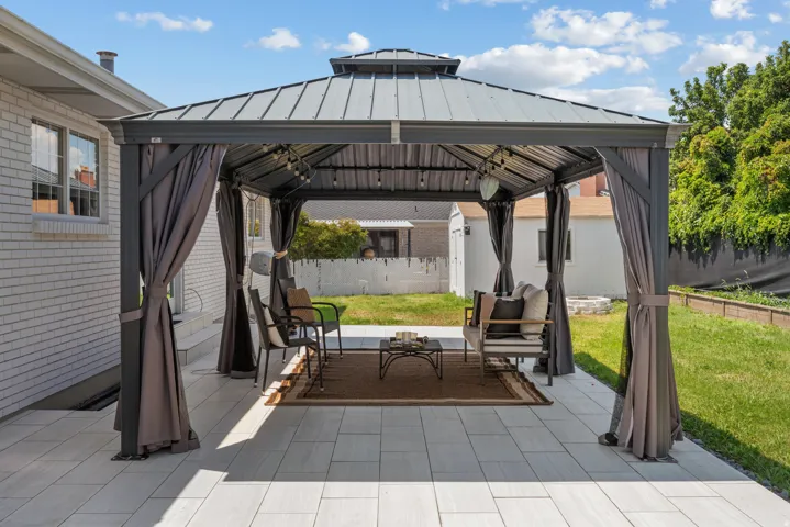 Spacious outdoor patio featuring a large gazebo with a metal roof and privacy curtains