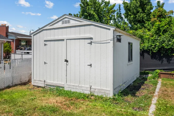 Freestanding storage shed with white exterior siding and double barn doors