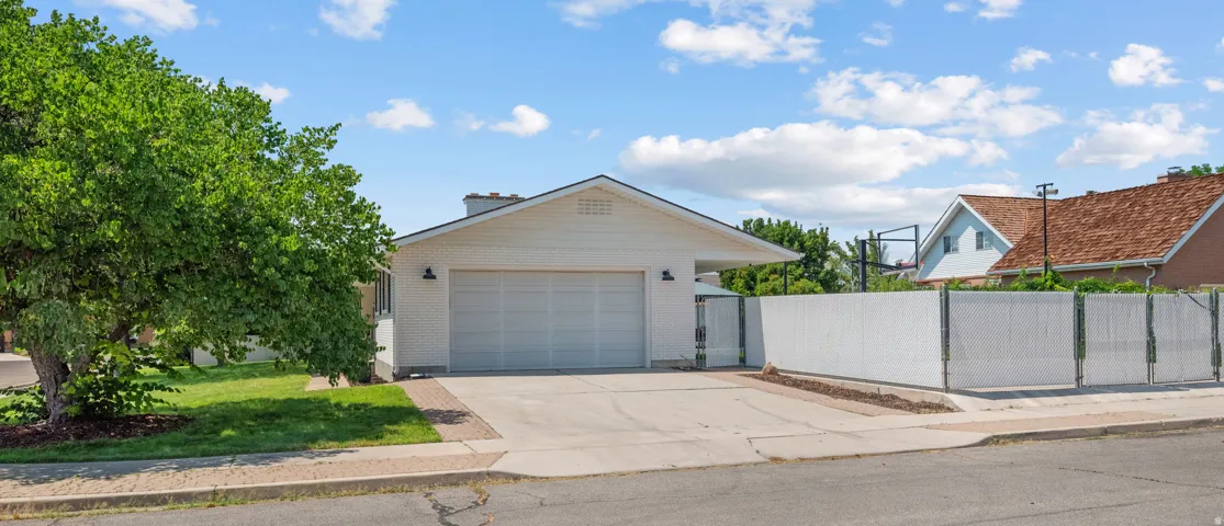 White siding exterior featuring a two-car garage, covered entry, and a white privacy fence