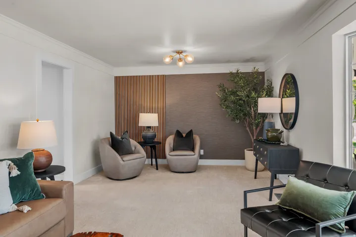Neutral-toned interior with crown molding, carpet flooring, a decorative wood slat wall feature, and a textured accent wall