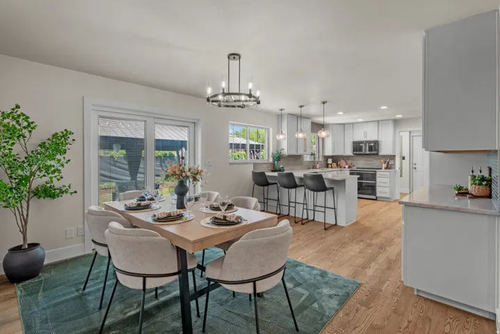 Open concept living space featuring wood-finish flooring, a contemporary dining area with a circular chandelier, and sliding glass doors