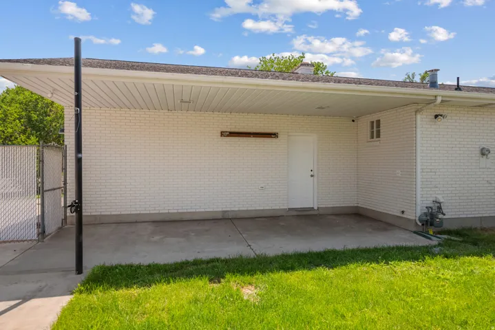 Covered patio area featuring white brick siding and a concrete pad