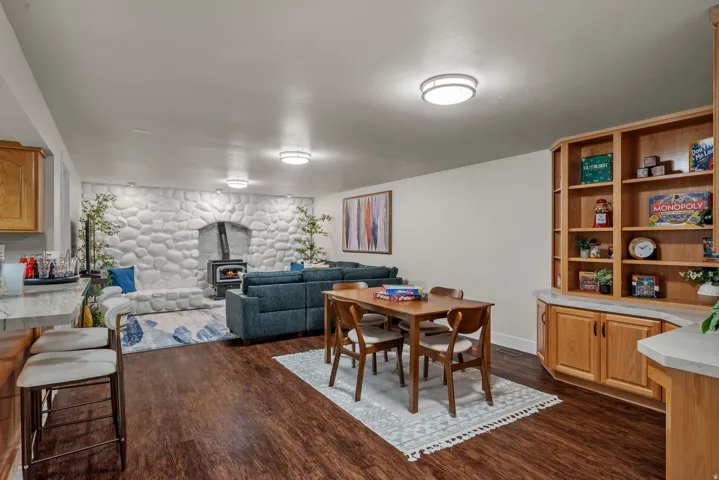 Spacious entertainment area featuring wood-finish flooring, a prominent stone-clad fireplace with a wood-burning stove, and built-in oak cabinetry