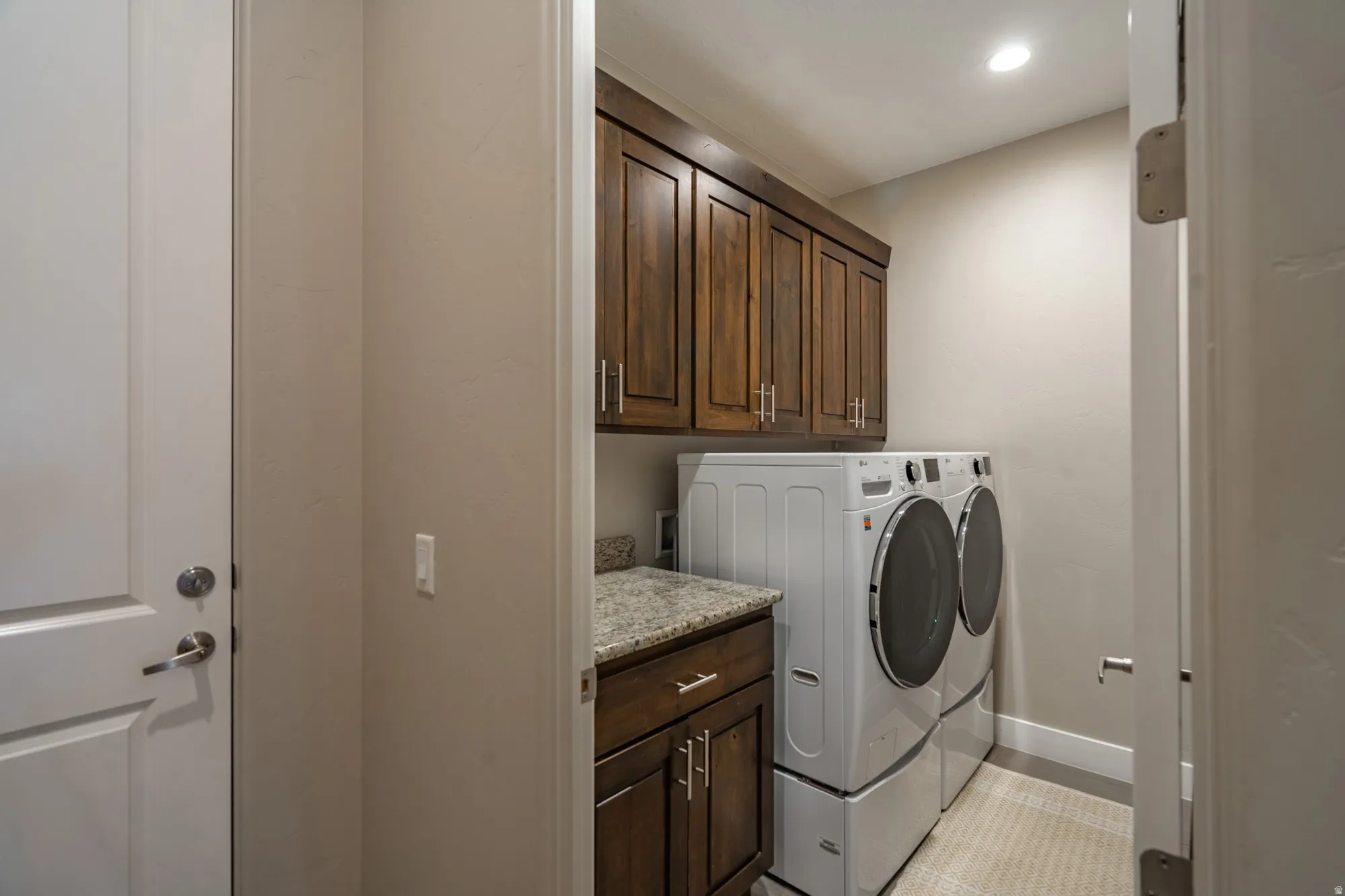 Dedicated laundry area featuring wood cabinetry, a light-toned countertop, and recessed lighting