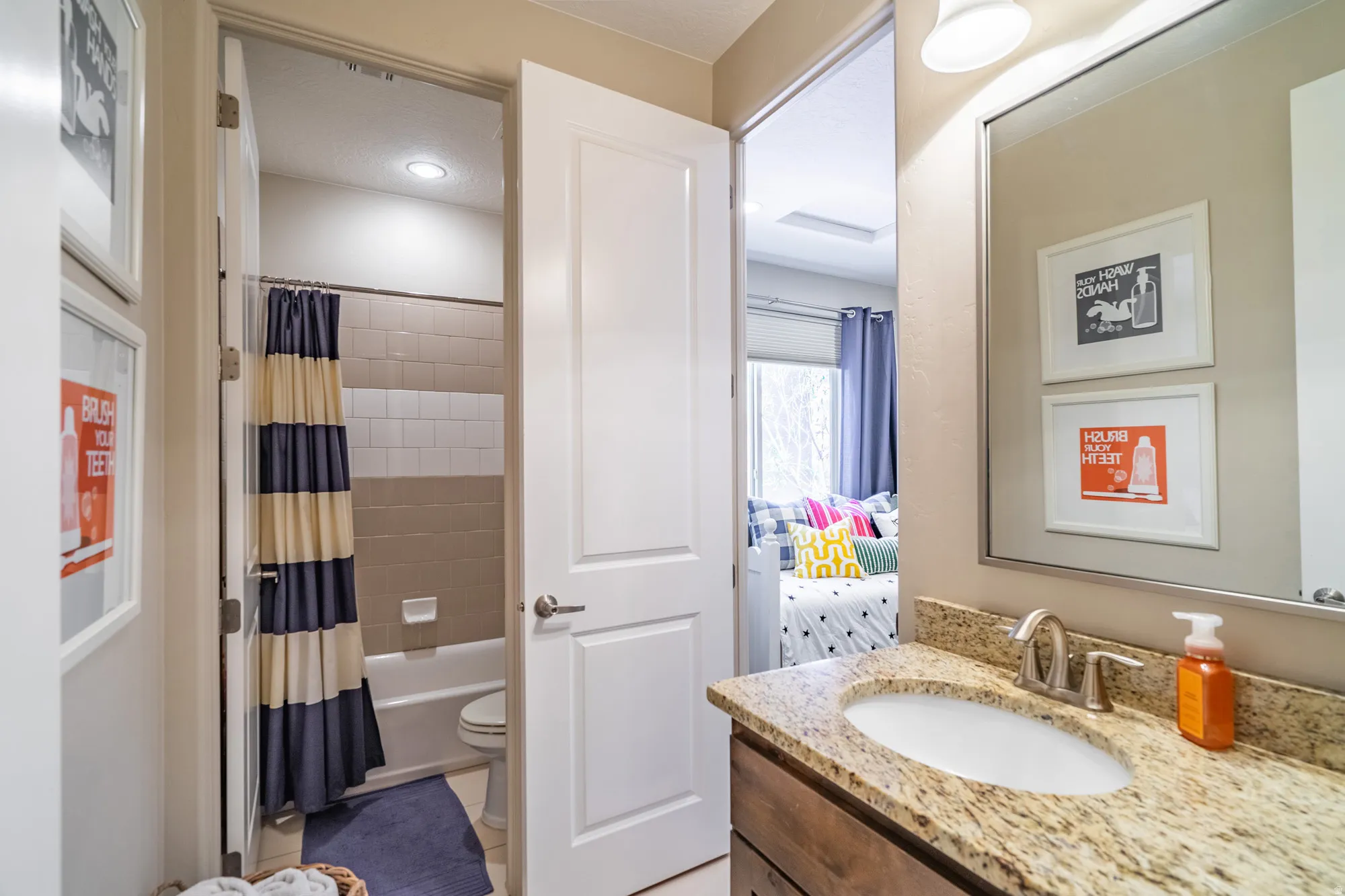 Bathroom featuring a granite countertop vanity with an undermount sink, brushed nickel faucet, and a large wall-mounted mirror