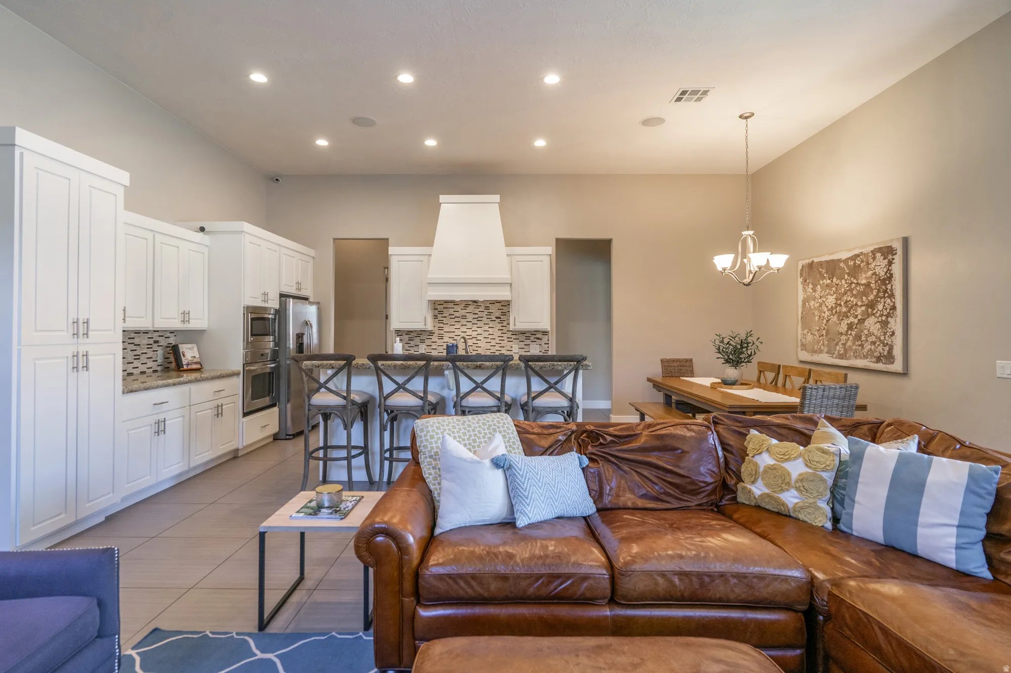 Spacious open-concept living area featuring a kitchen with white cabinetry, stainless steel appliances, and a tiled backsplash