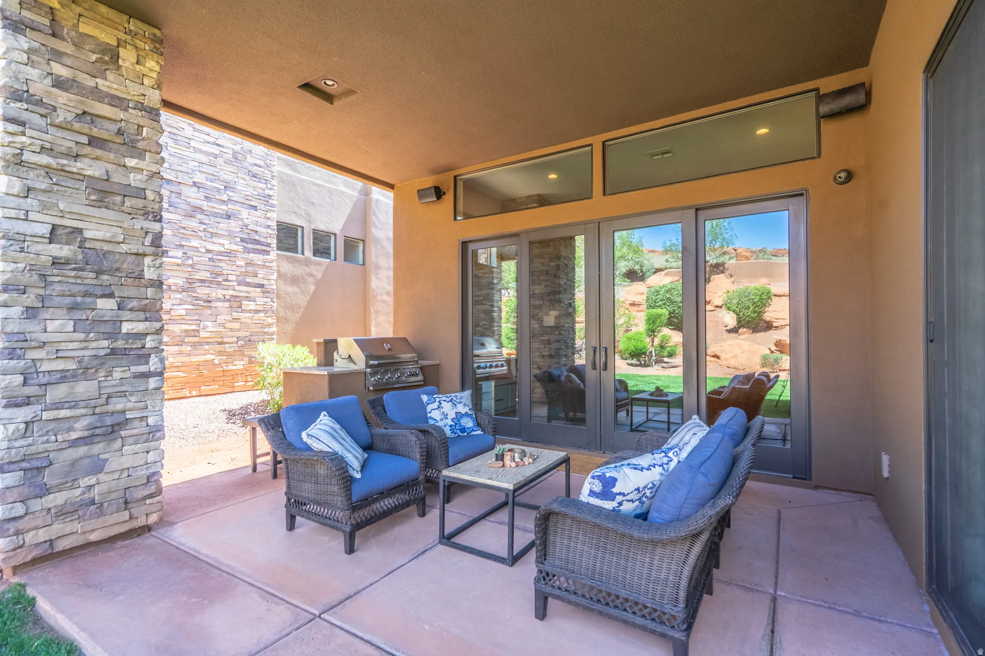 Covered patio featuring a stone veneer support column and integrated outdoor kitchen