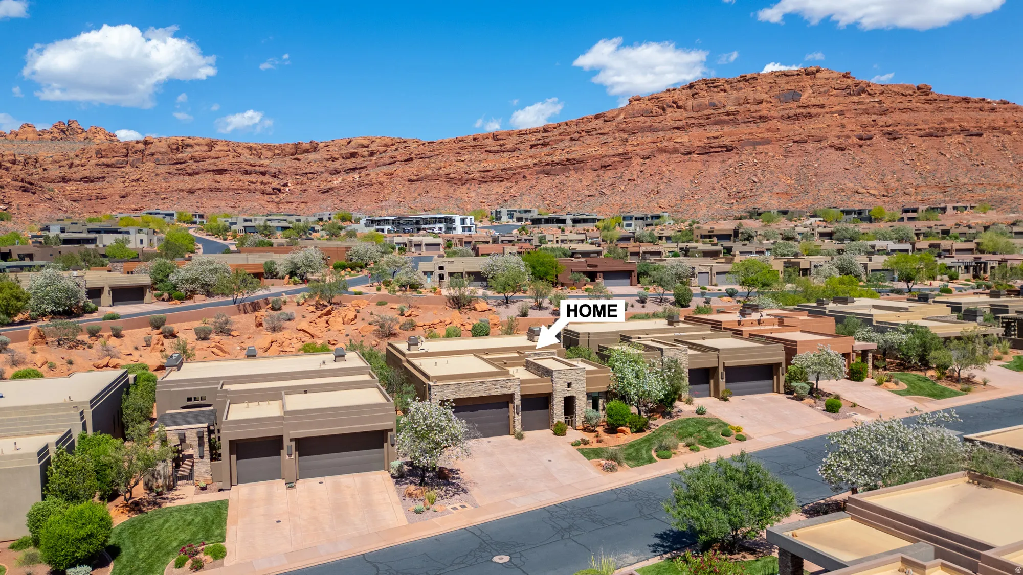 Modern architectural home featuring a two-car garage, stone facade accents, and desert landscaping