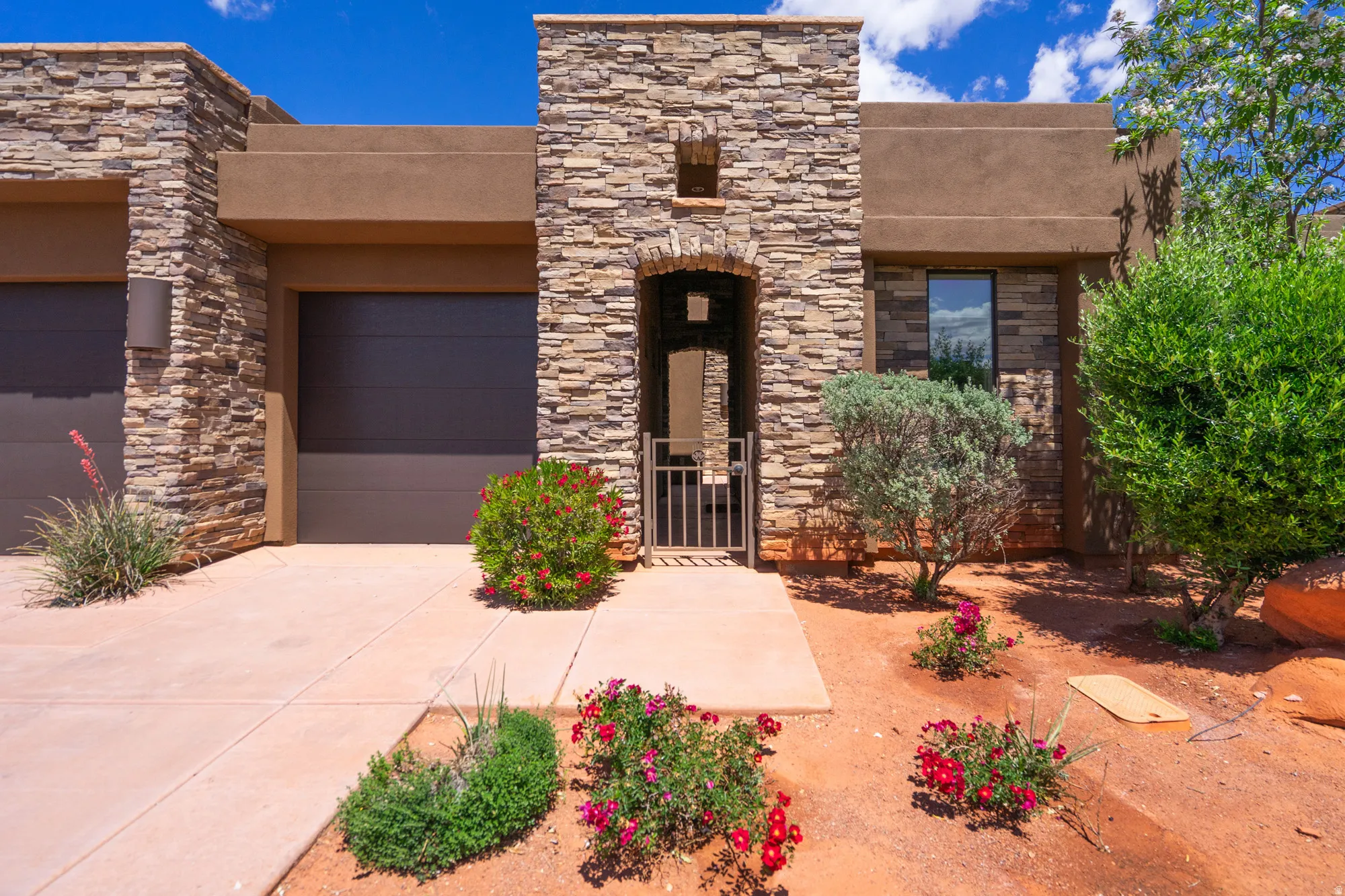 Stone and stucco exterior featuring a gated arched entry