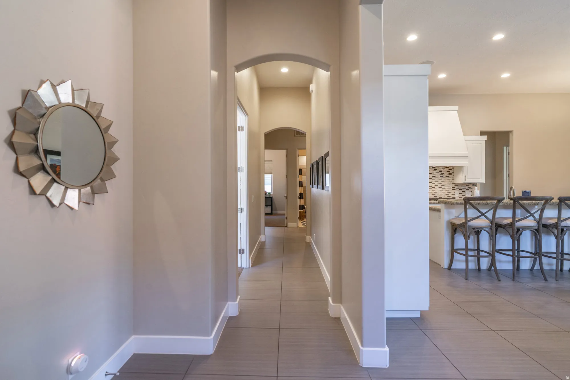Interior hallway featuring arched doorways, light neutral wall tones, and tile flooring