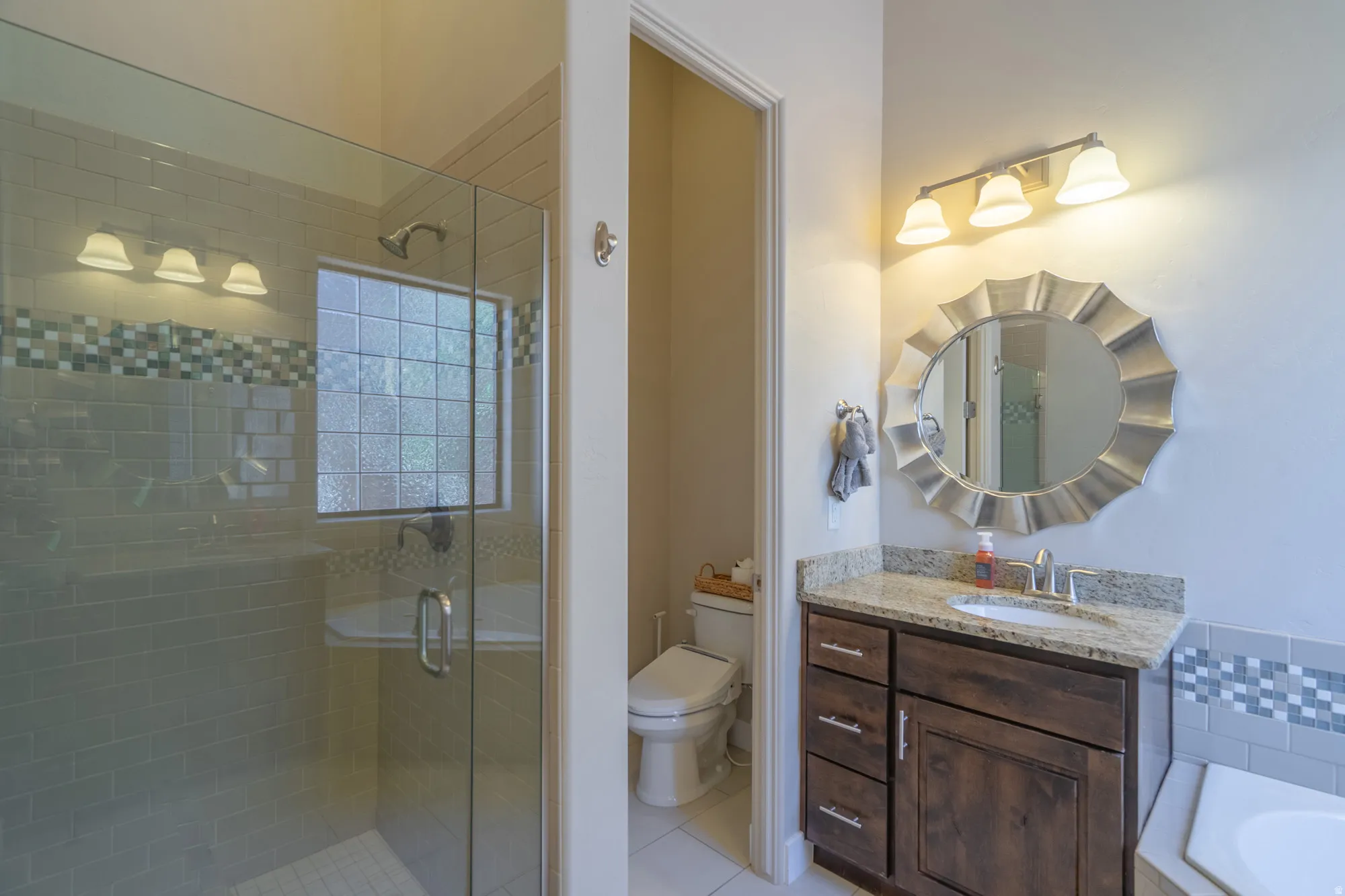 Bathroom featuring a glass-enclosed shower with tile surround, a built-in bench, and a privacy glass block window