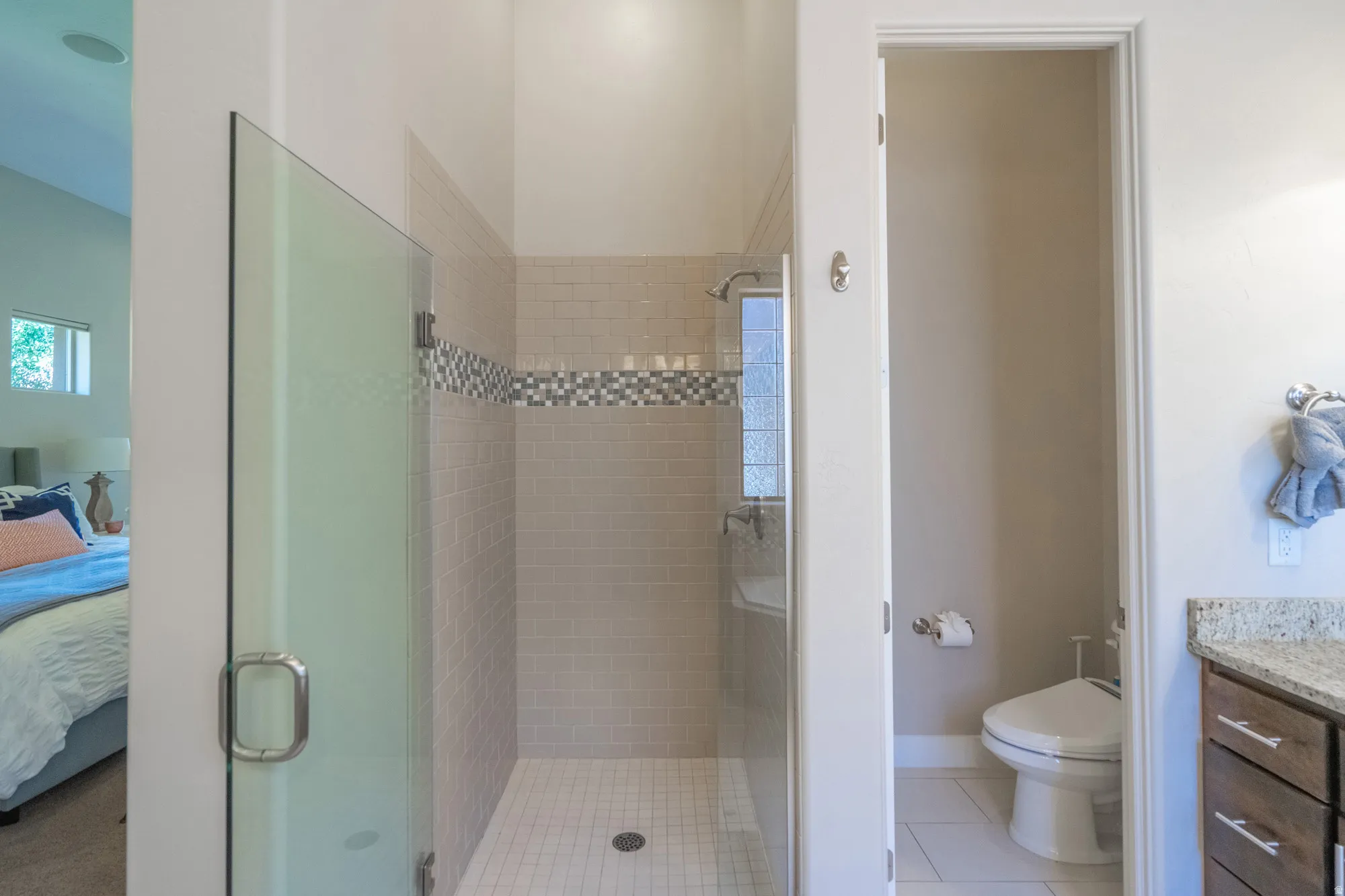Glass-enclosed shower with subway tile surround and decorative mosaic accent