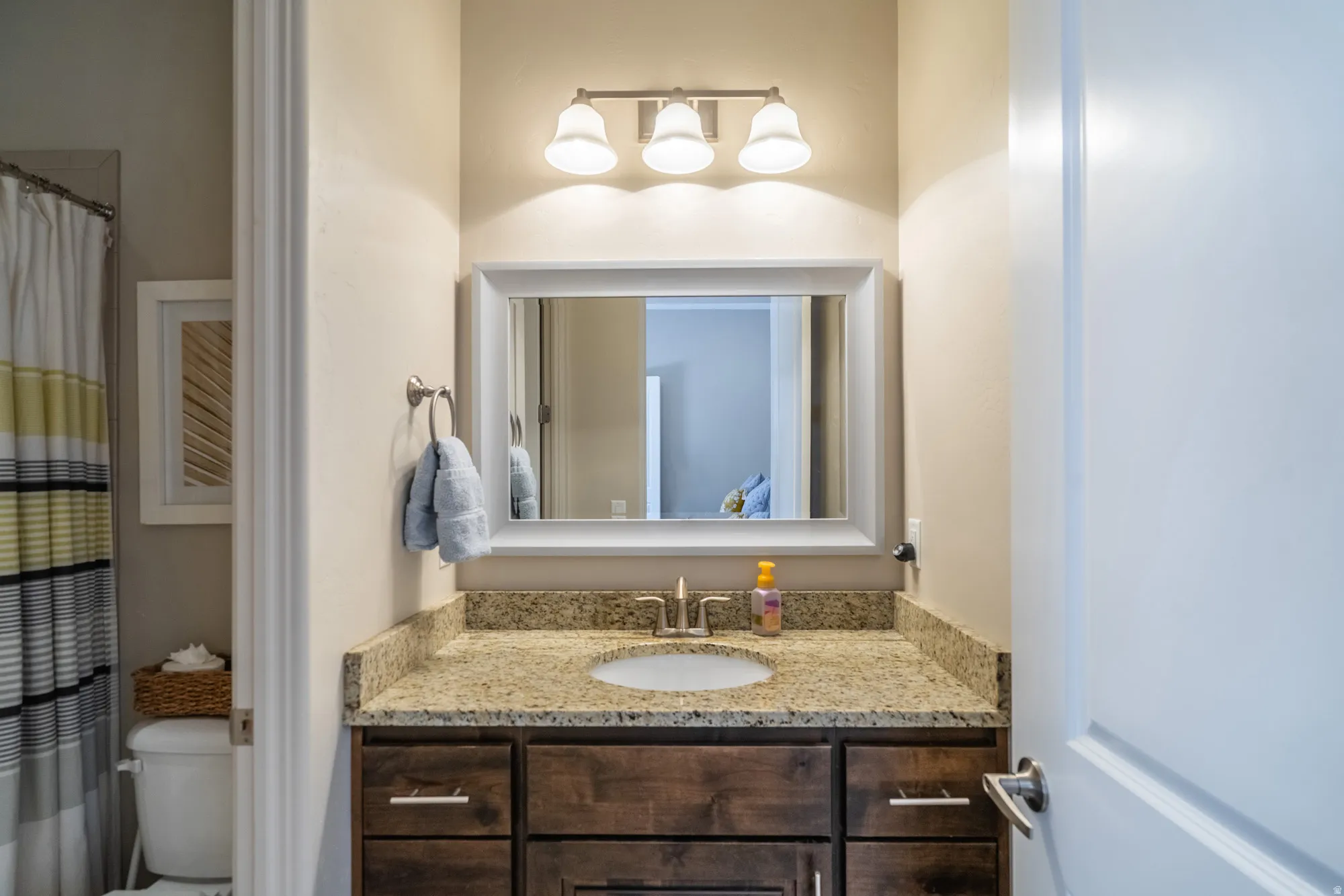 Bathroom vanity featuring a granite countertop, undermount sink, and dark wood cabinetry with brushed nickel hardware