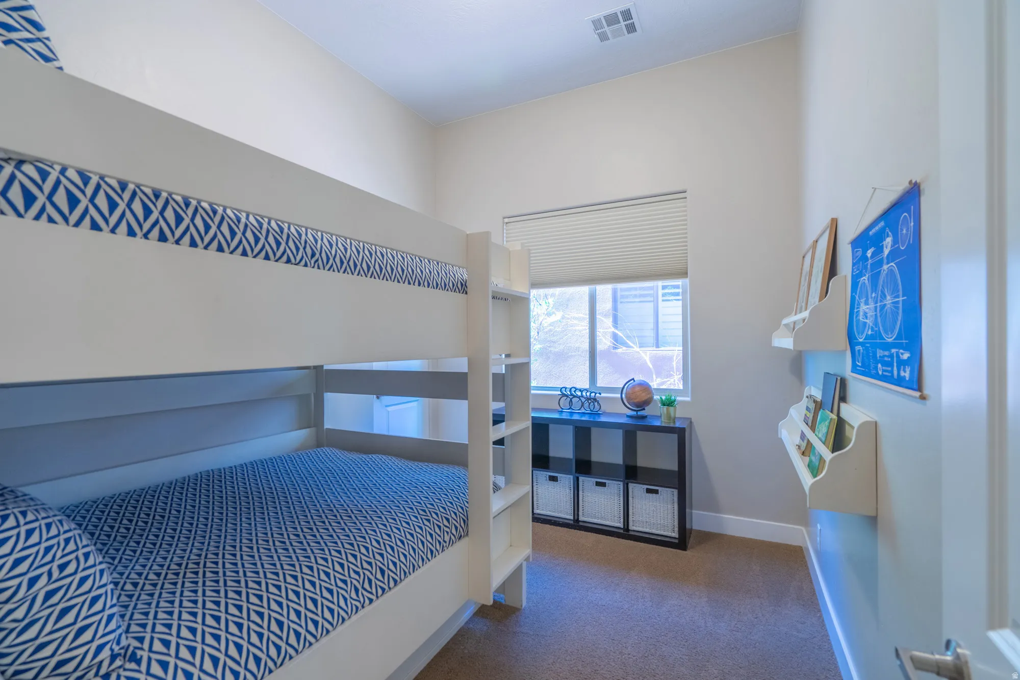 Carpeted room featuring a window with blinds, white walls, and built-in shelving
