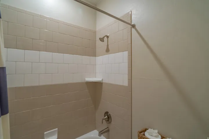 Bathtub shower combination with two-tone tiled surround, brushed nickel fixtures, and wall-mounted shower head