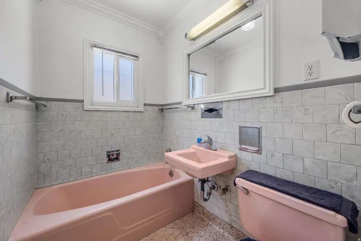 Bathroom featuring a pink porcelain bathtub, coordinating wall-mounted sink, and toilet