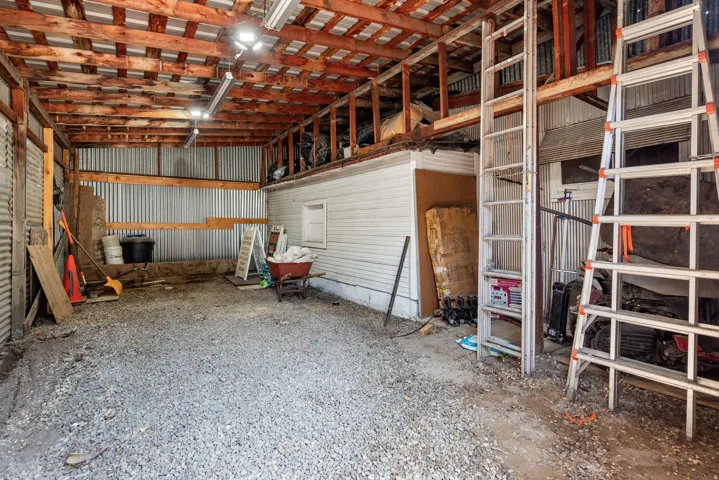 Expansive open-air structure featuring a gravel floor and exposed wood beam ceiling