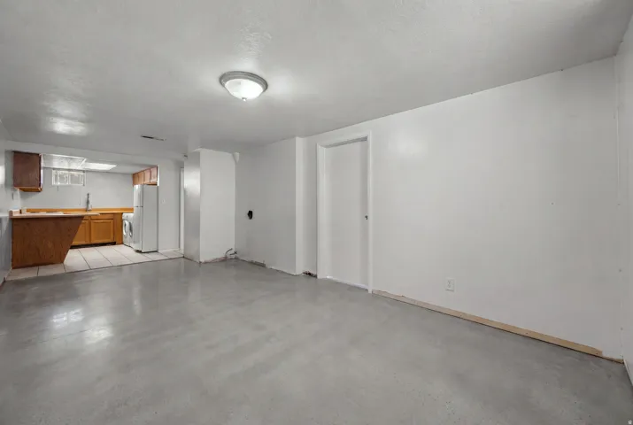 Spacious room featuring light gray flooring, white walls, and a flush mount ceiling light