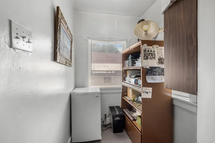 Compact utility space featuring a single window with blinds and a built-in wall cabinet with wood-finish doors