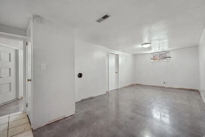 Expansive interior space featuring light-colored walls and grey concrete flooring