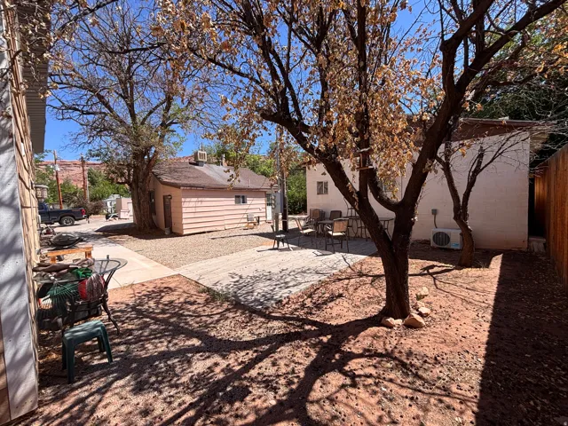 Outdoor area featuring mature trees, a gravel yard, and paved pathways