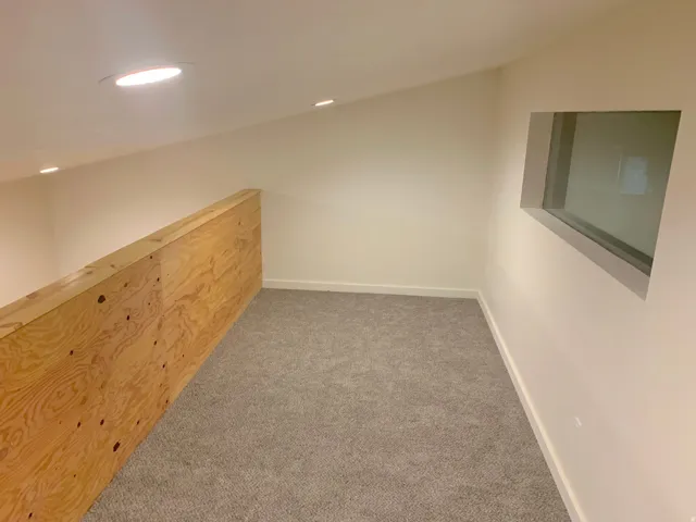 Carpeted loft area with recessed lighting, a sloped ceiling, and a wooden half-wall