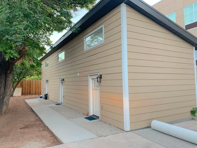 Two-story building featuring tan horizontal siding and multiple entry doors