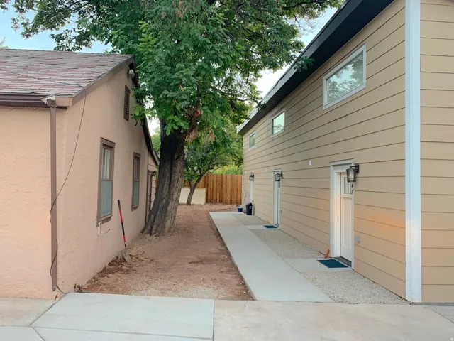 Two distinct structures featuring a concrete walkway, mature tree, and exterior lighting fixtures