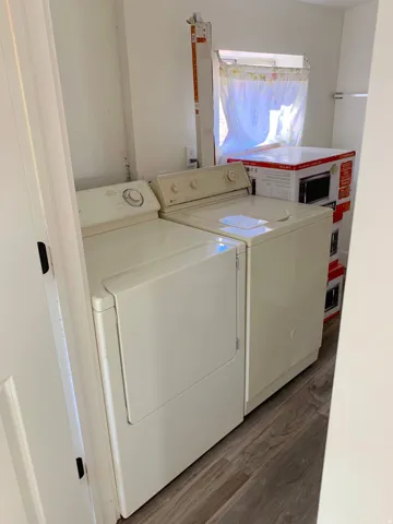Dedicated laundry area featuring wood-finish flooring