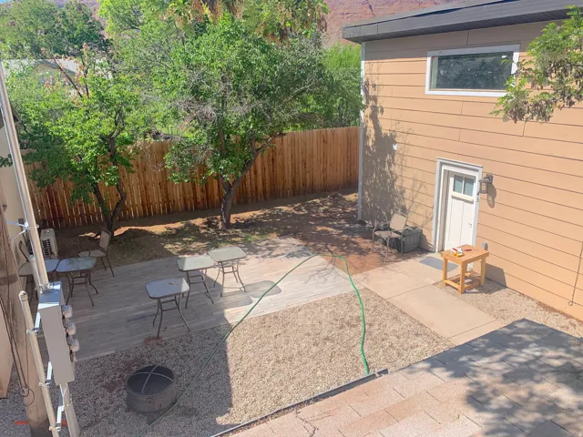 Expansive backyard featuring a wood privacy fence, mature trees, a multi-level deck, and a gravel patio area