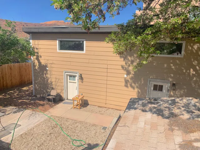 Exterior wall with horizontal siding, two white-framed windows, and two entry doors each featuring an exterior wall lantern