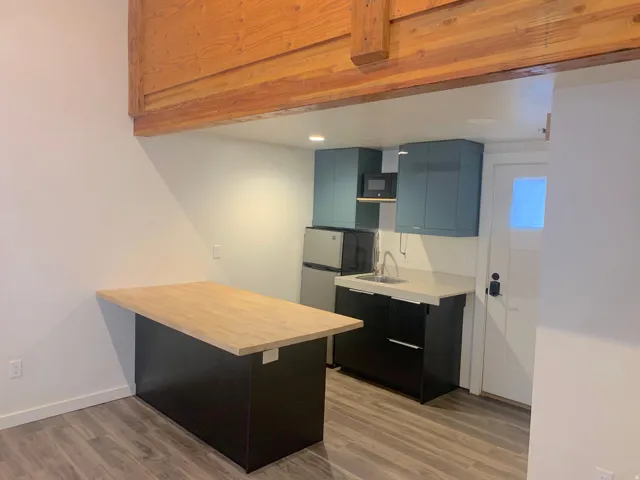 Kitchenette featuring quartz countertops, stainless steel sink, and teal upper cabinetry