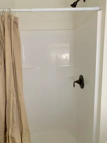 White shower enclosure with a dark-finished shower head and single-handle faucet