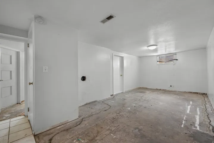 Spacious room featuring a concrete floor, white painted walls, and a ceiling-mounted light fixture