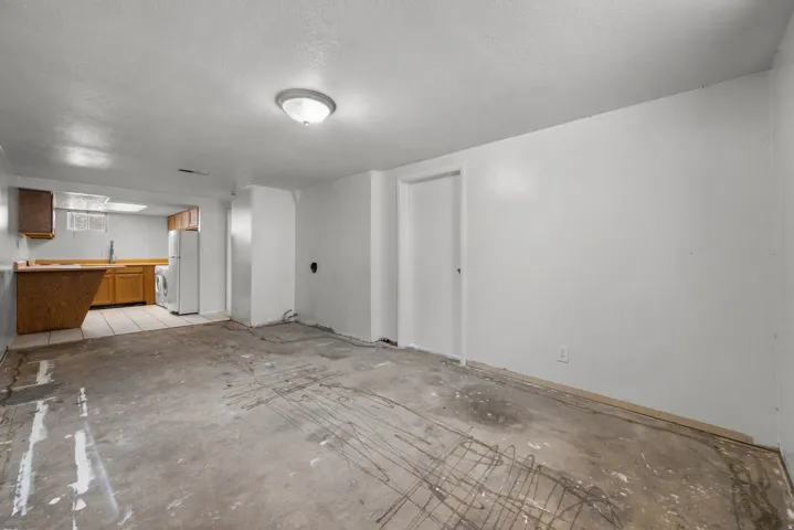 Open concept space featuring a partial kitchen with wood cabinetry, a white refrigerator, and a washer