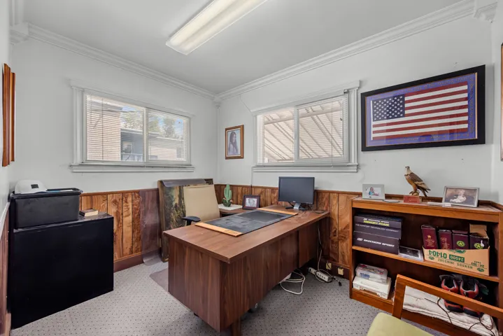 Room featuring wood-paneled wainscoting, light-colored walls, and two windows