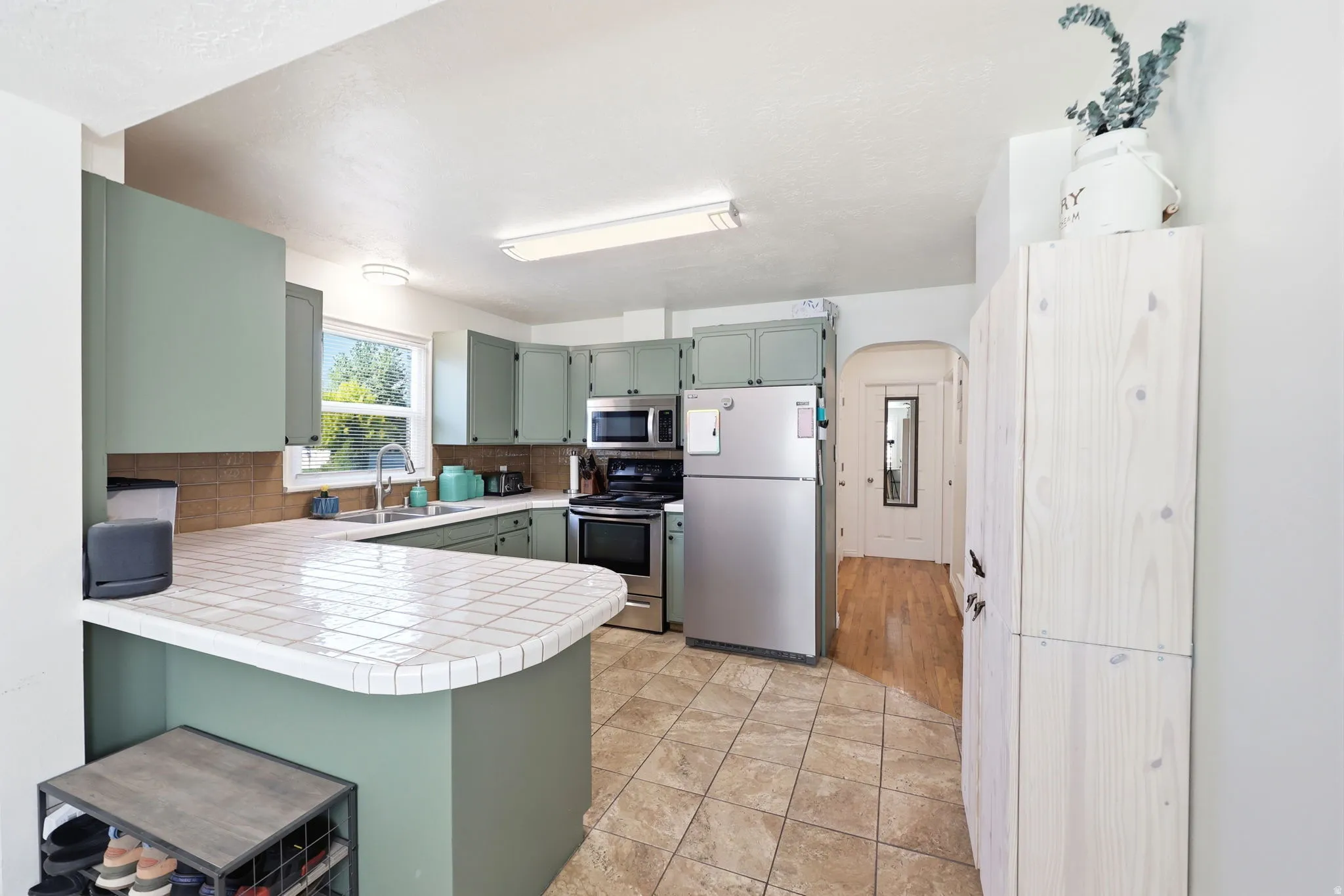 Kitchen featuring sage green cabinetry, tiled countertops, and stainless steel appliances