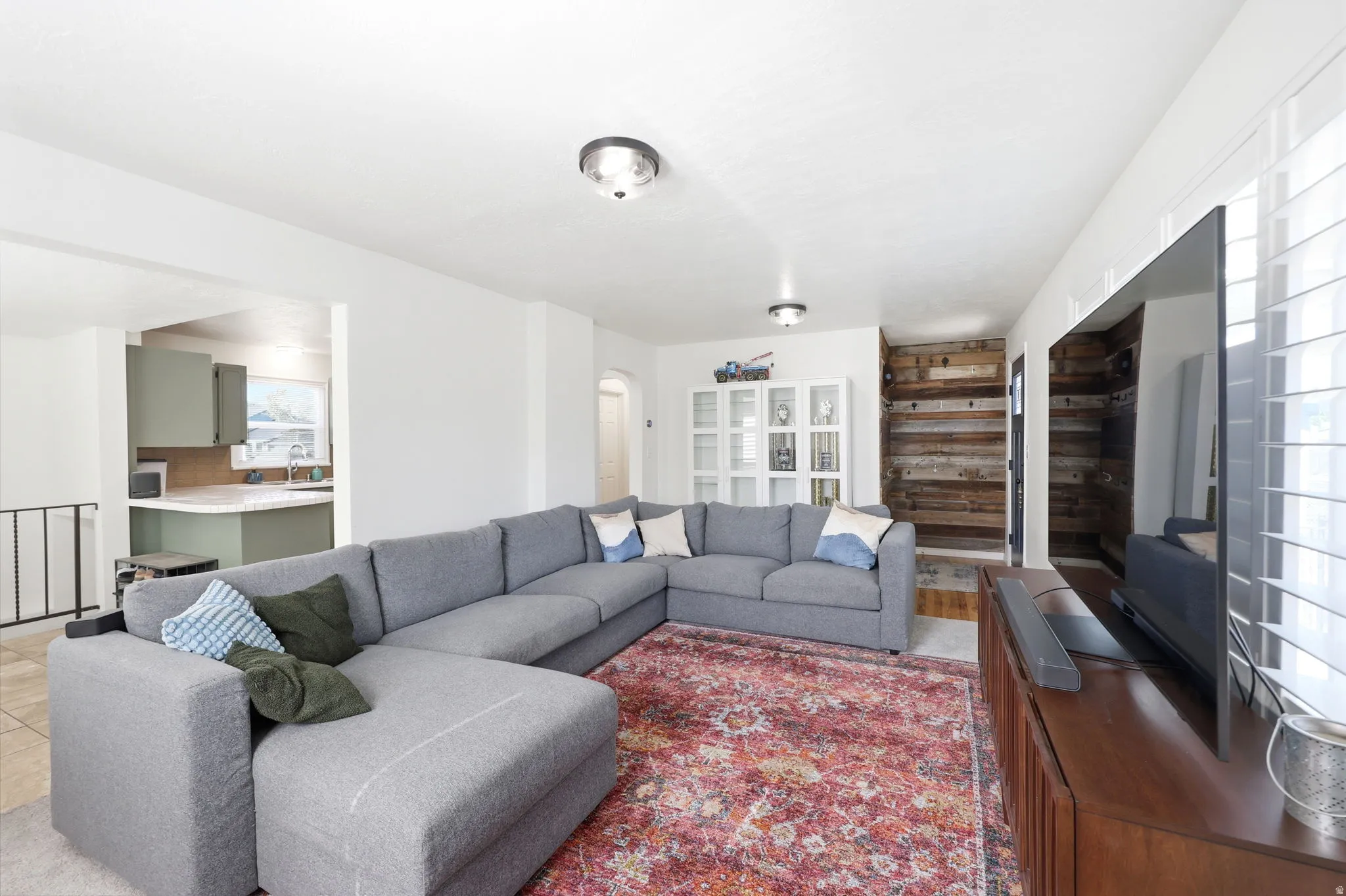 Spacious living area featuring white walls, wood-finish flooring, and a rustic wood accent wall