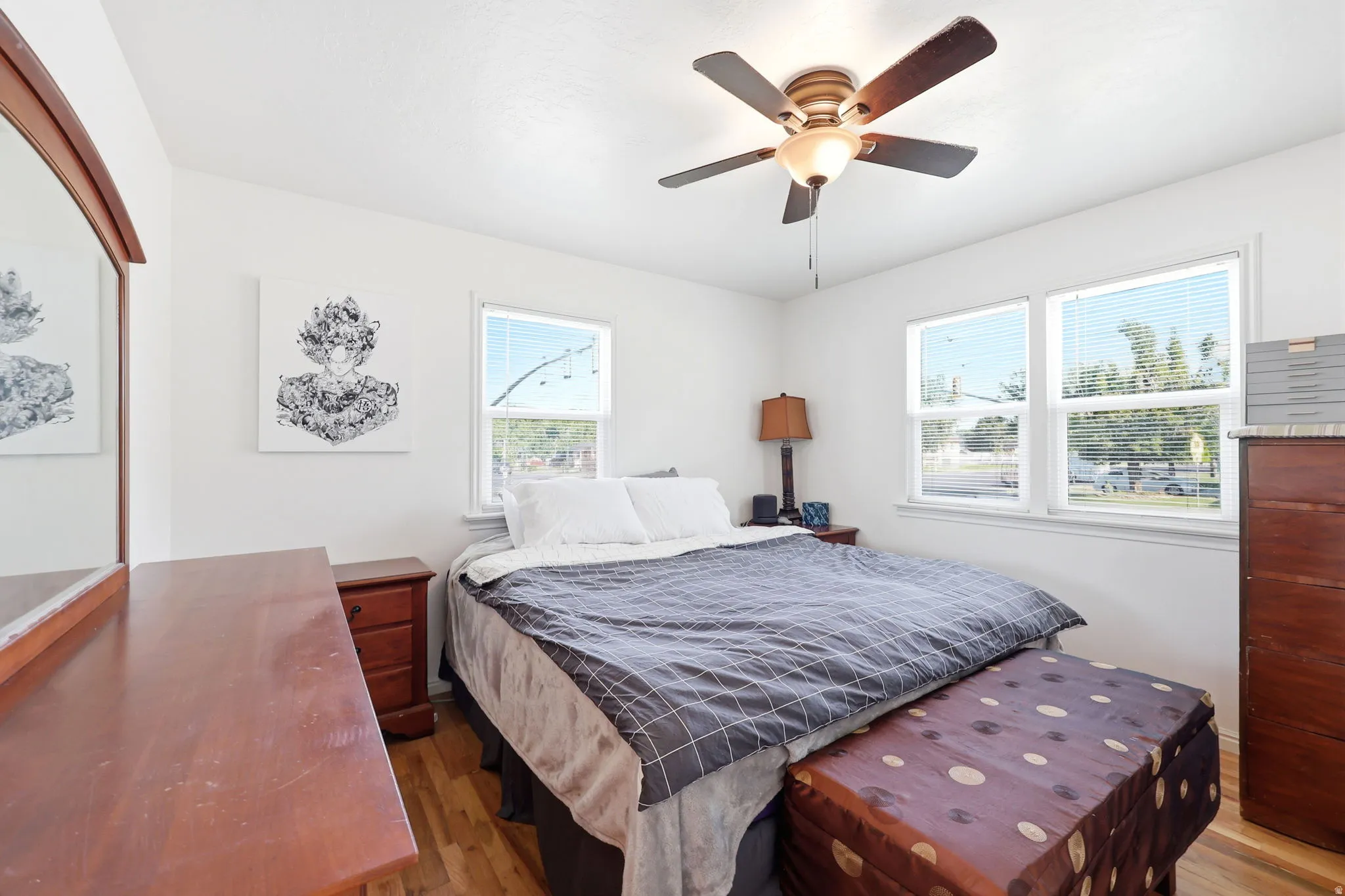 Bright room featuring wood-finish flooring, white walls, and a ceiling fan with integrated lighting